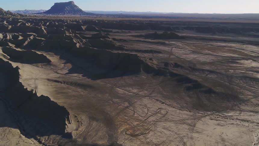 Dirt and hills cover a rural landscape at sunset