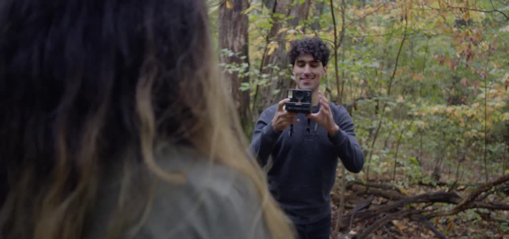 Man takes a picture of a woman in the woods