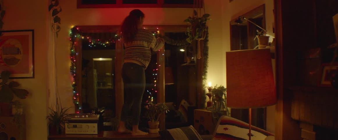 Woman hangs christmas lights around a window