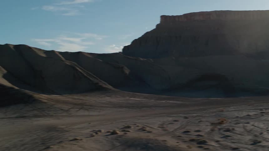 The sun shines over mountains and dirt hills