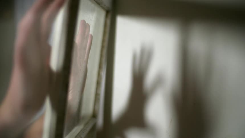 Person putting their hands on pane glass
