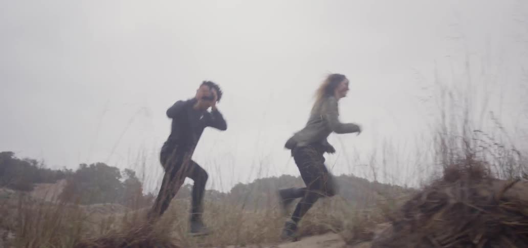 A man and woman are running through a desert