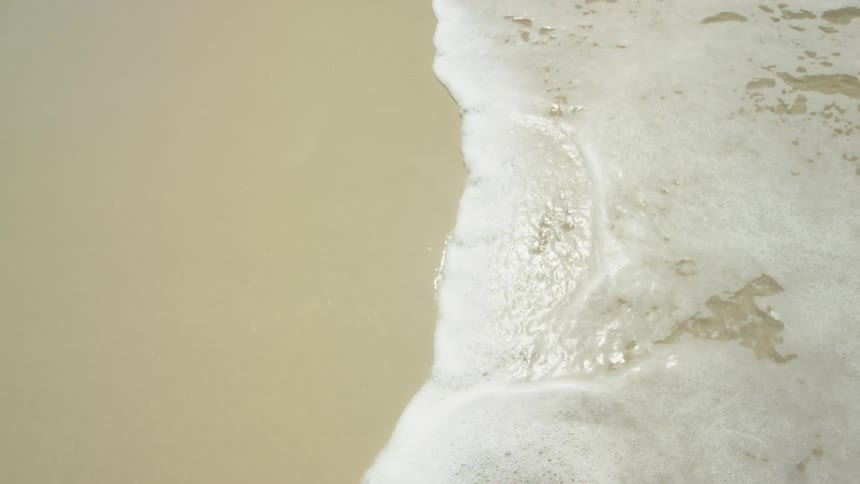 The water slowly hits the shore on a sunny day