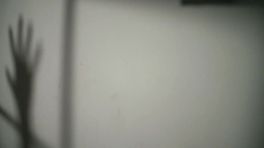 Shadow of a person's hand on a white wall