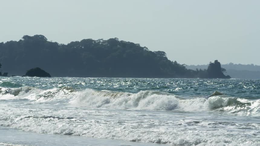 Tall and choppy waves flow towards the beach shore