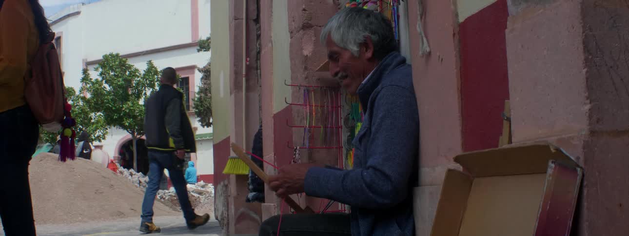 A man ties ribbon while sitting on the sidewalk