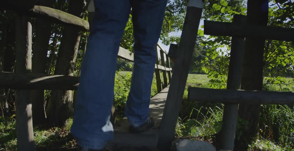 Someone is walking across a small very narrow bridge