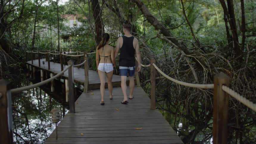 Man and woman walk on a low bridge over water