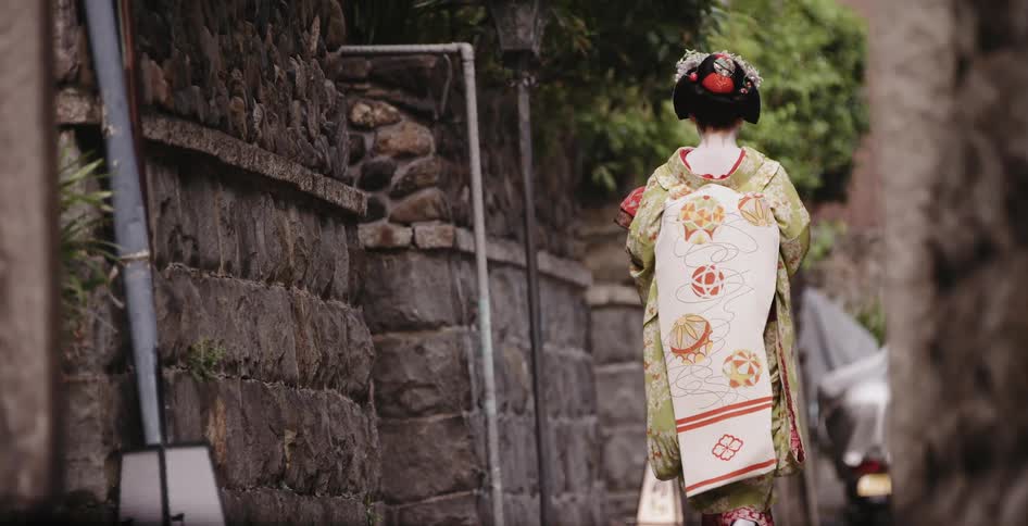 Woman wears a kimono as she walks down the sidewalk
