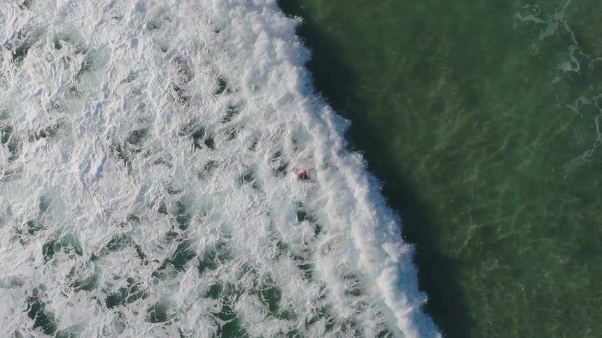A surfer is swimming out into the waves