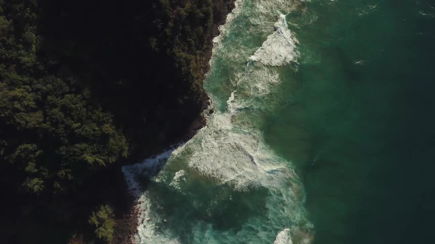 Waves are crashing against cliffs in daylight