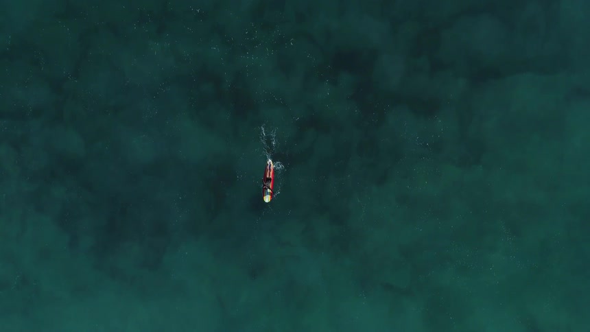 The person is rowing on the surfboard below