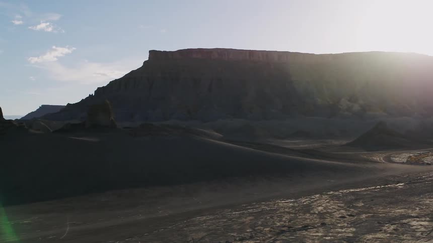 The sun shines down on rock formations and dunes
