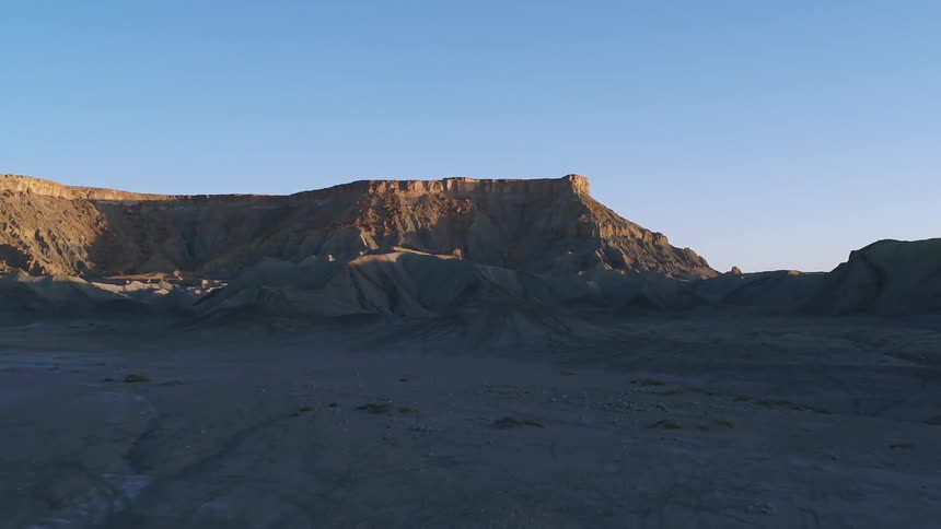 Flat topped hills sit under a bright blue sky