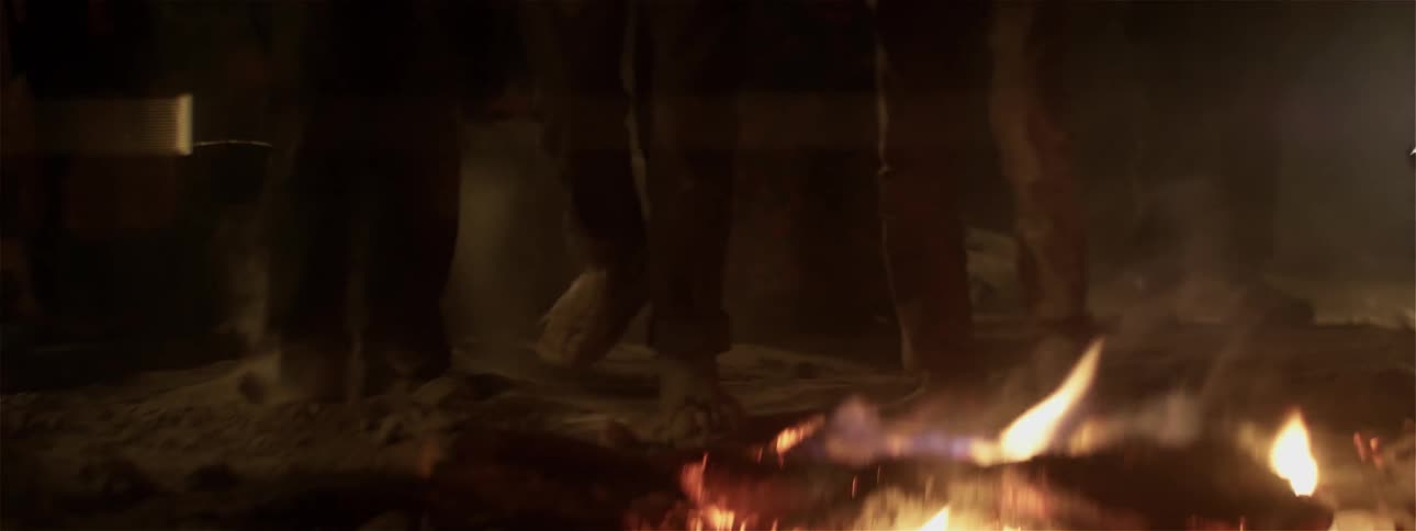 People dance around a fire at night