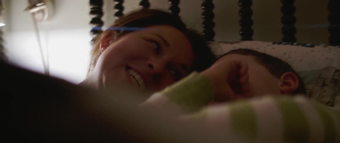 Woman and child lying in bed while talking and smiling