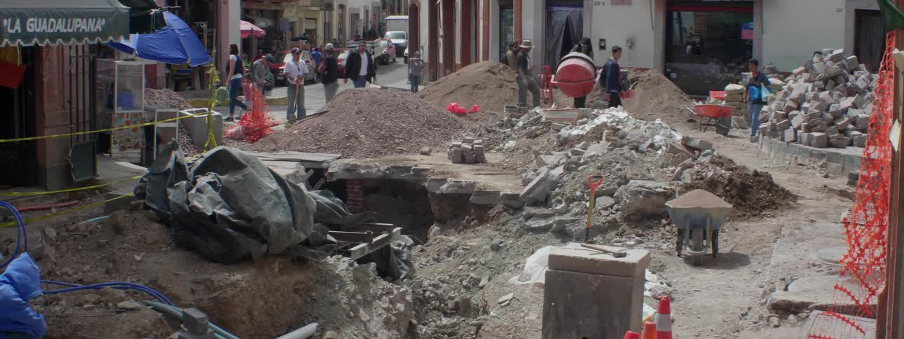 Crowd of people walk near some cement debris