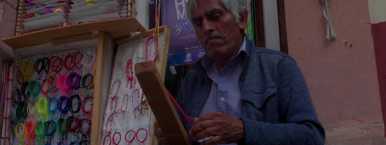 A man ties pink ribbon the street