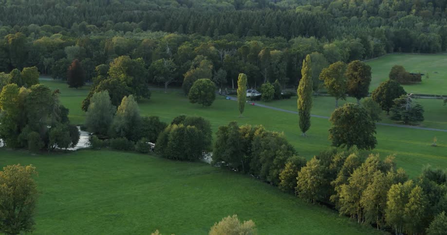 Boats are anchored in the canal around green fields and trees