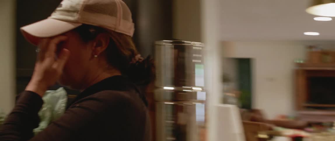 A woman walks to put food into the fridge