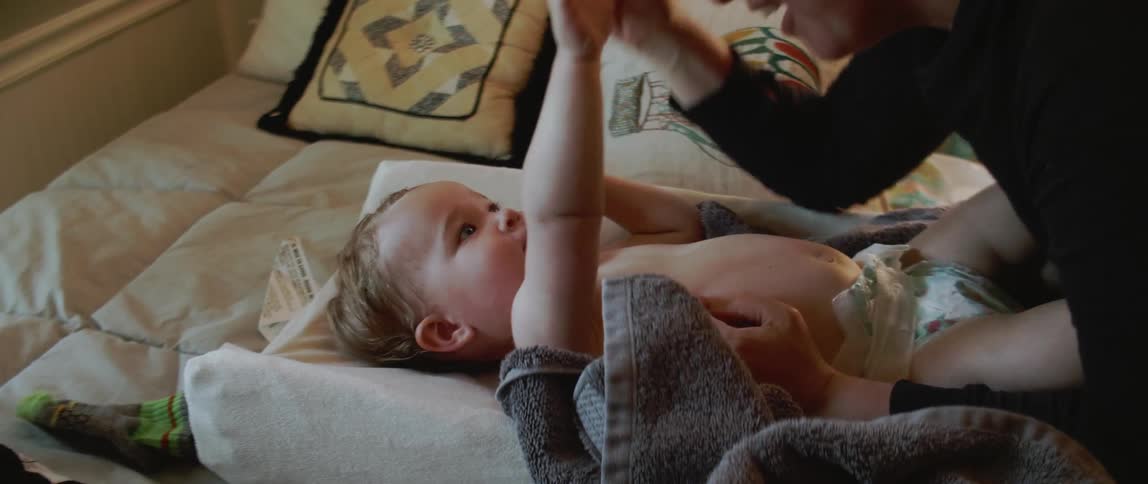Woman plays with a baby and puts a hat on its head