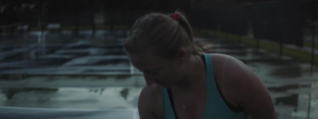 Woman playing tennis outside on wet court