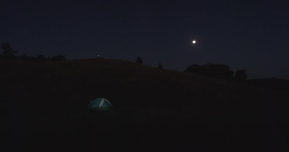 People are in a tent on the hill at night