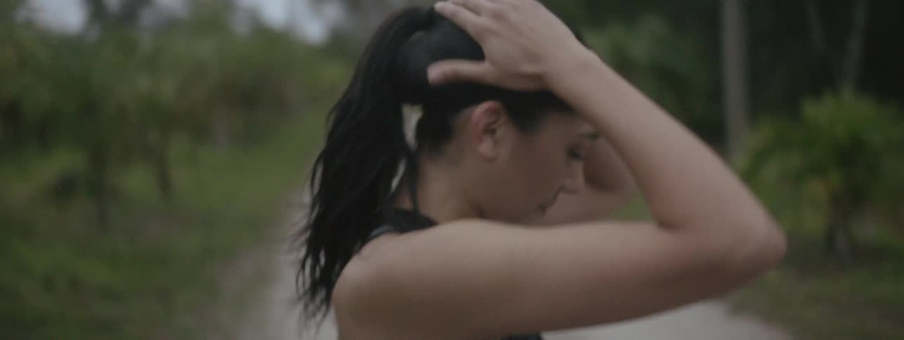 A woman stops to catch her breath while jogging on a dirt road