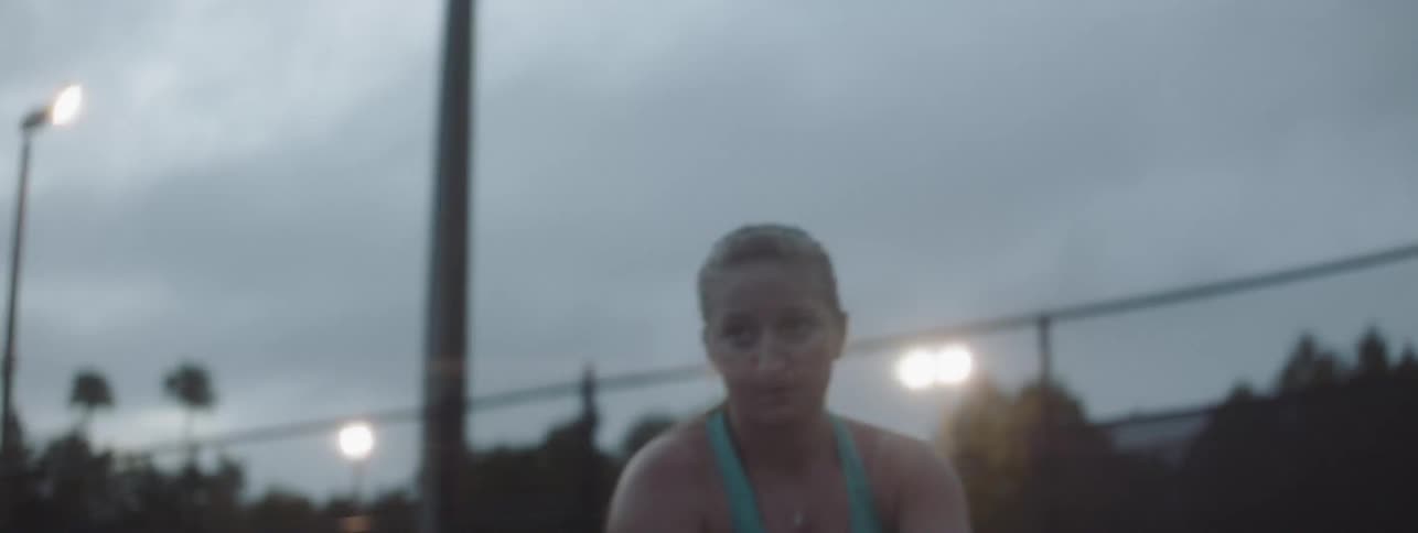 A woman winds up and hits the tennis ball