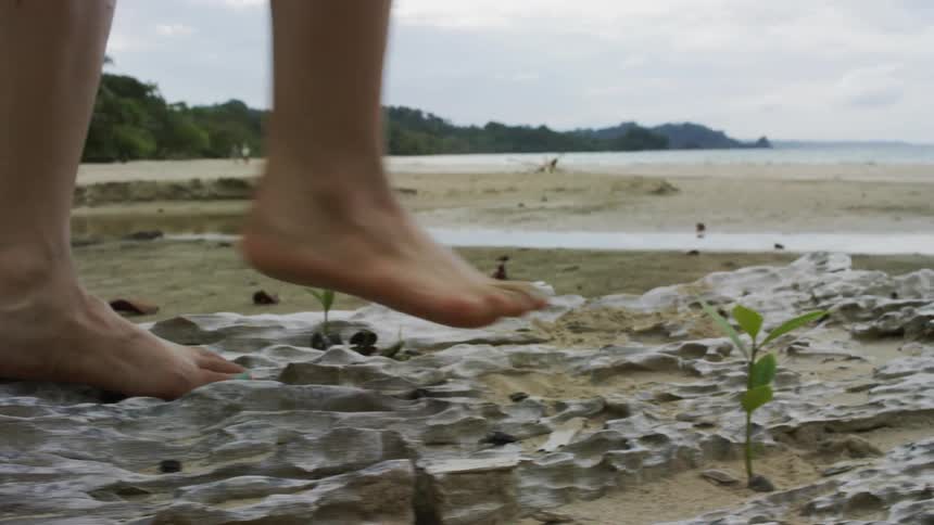 Person steps on rocky land near the beach