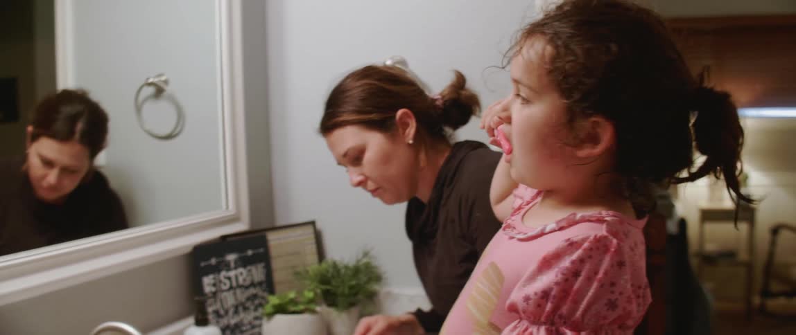 A woman and child are brushing their teeth