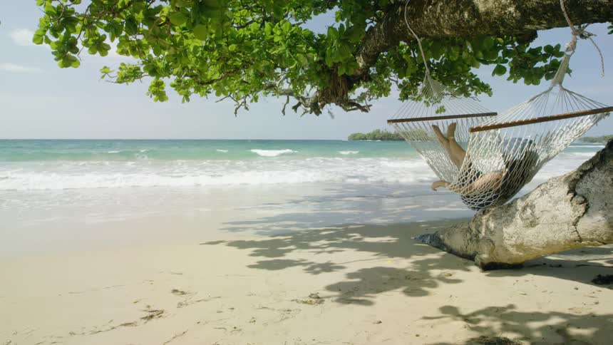 Person lies in a hammock at the beach