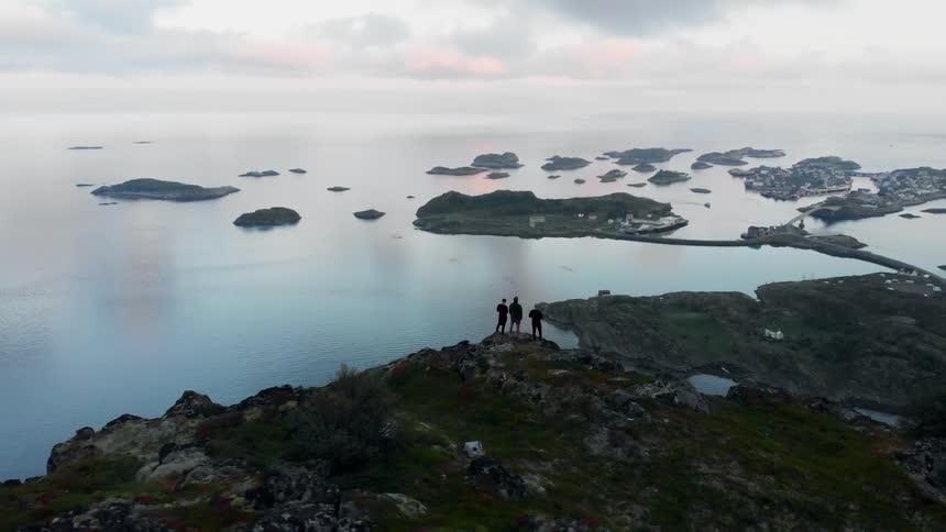 Hikers stand on a coastal mountain peak at sunset