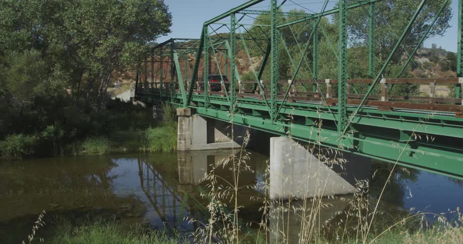 A car travels over the green bridge