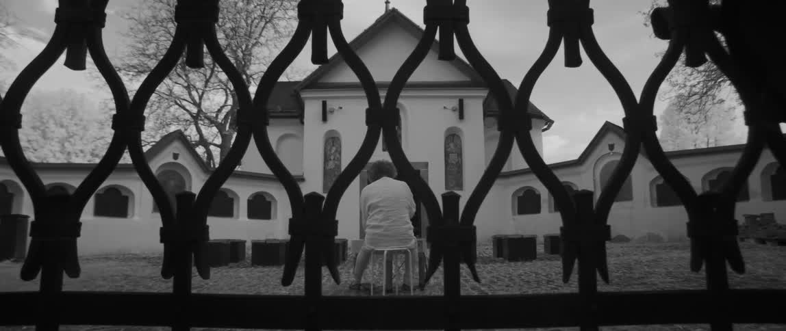 Woman sits on a stool in front of a church