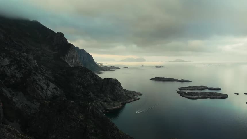 The heavy clouds touch the mountains near the water