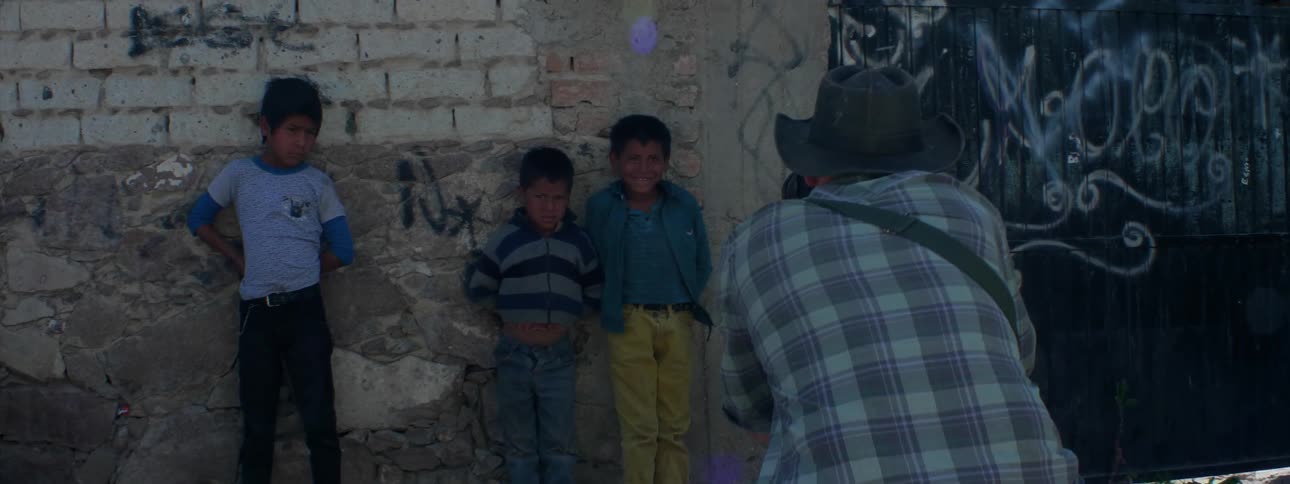 Man takes photo of three boys leaning against a wall