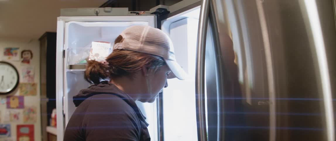 A woman talks as she puts groceries away in the refrigerator