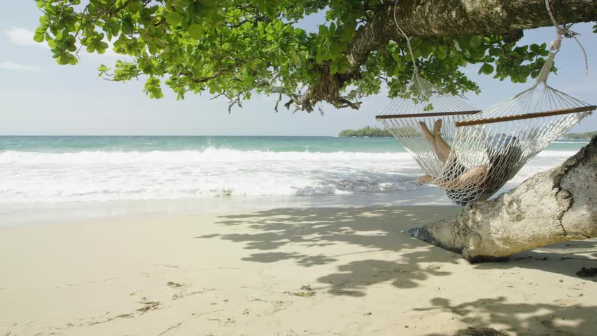 Woman relaxes in a hammock on a beach