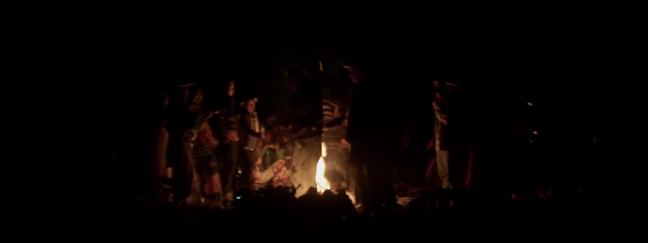 People gather around a campfire at night