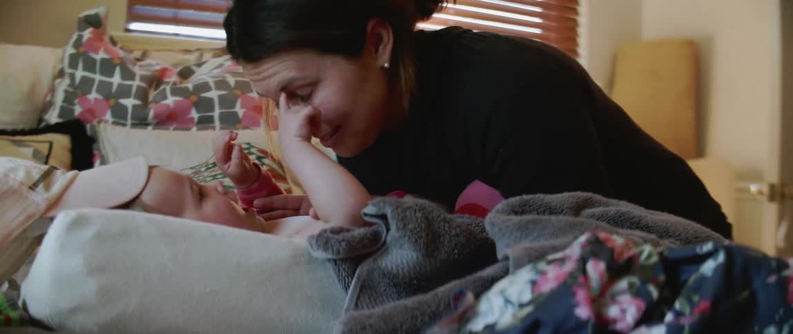Woman talks to a baby laying on a bed