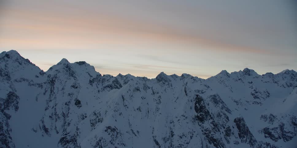 Snow covered mountains under a cloudy blue sky