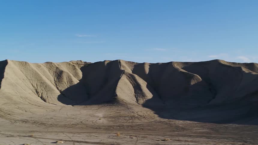 Dirt hills sit beneath a blue sky