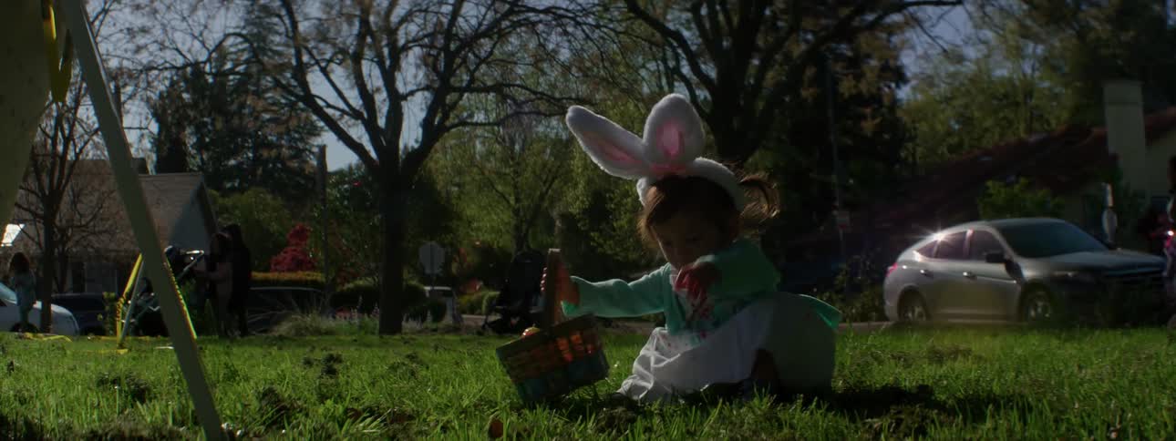 Child wearing bunny ears picks up basket and walks away