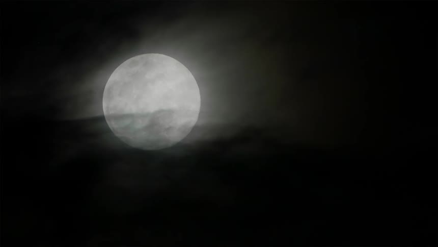 Clouds move gracefully in front of the moon