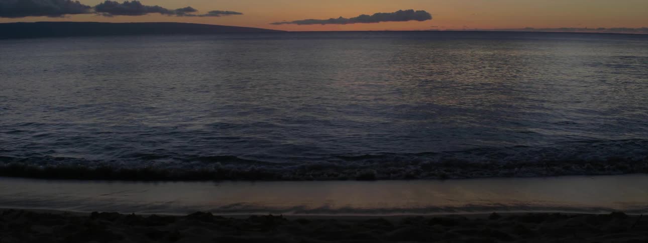 Water flows over sandy beach at sunset