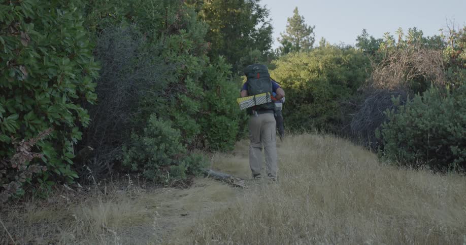 A man stumbles as he follows his friend on a hike