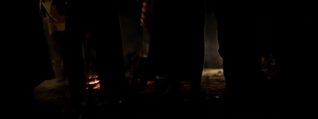 People dance next to a campfire at night