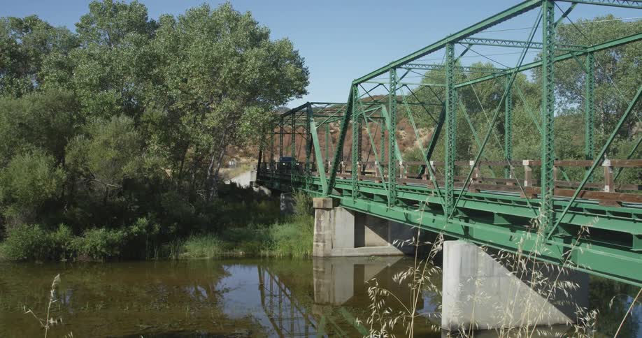 An suv crosses a rural bridge over a river