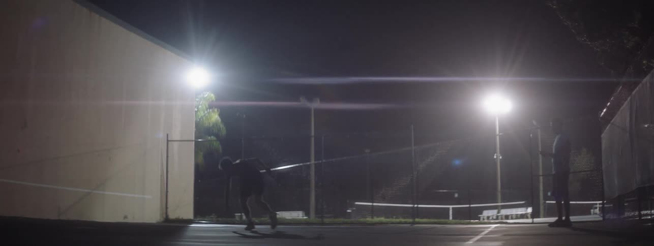 A man slips and falls on a tennis court